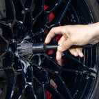 Using a detailing brush on a soapy black alloy wheel