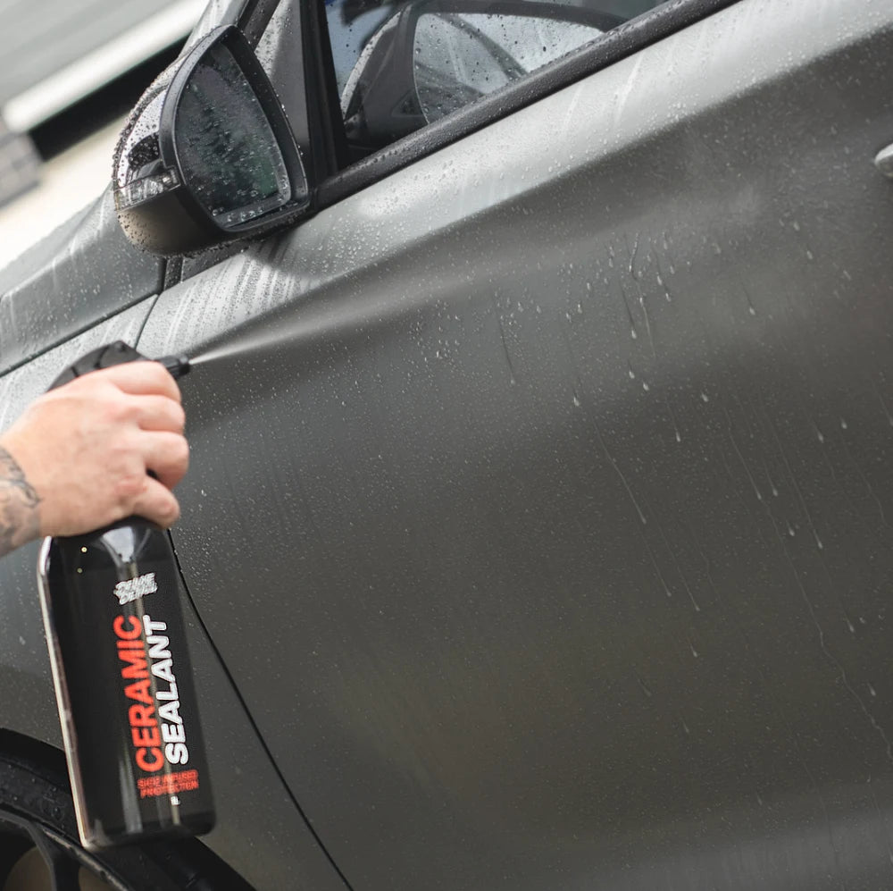 Spraying Deluxe Detail Ceramic Sealant onto the wet side panel of a car
