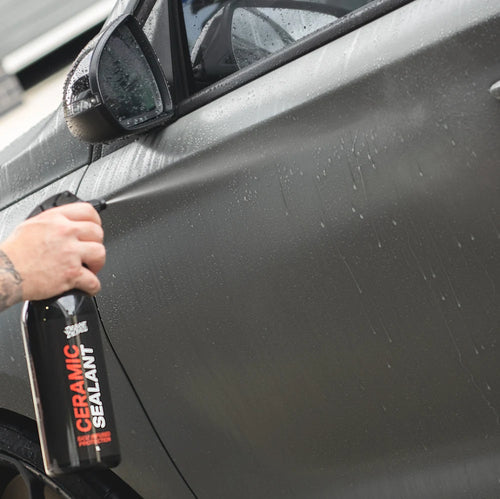 Spraying Deluxe Detail Ceramic Sealant onto the wet side panel of a car