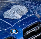 Deluxe Detail microfibre wash pad resting on the foam covered bonnet of a blue BMW M car