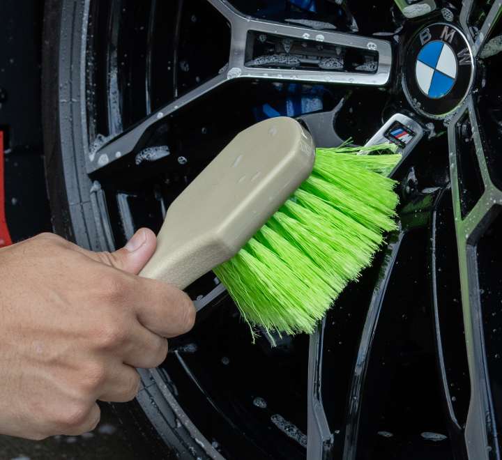Cleaning the face of a wet BMW alloy wheel with the green bristled wheel face brush