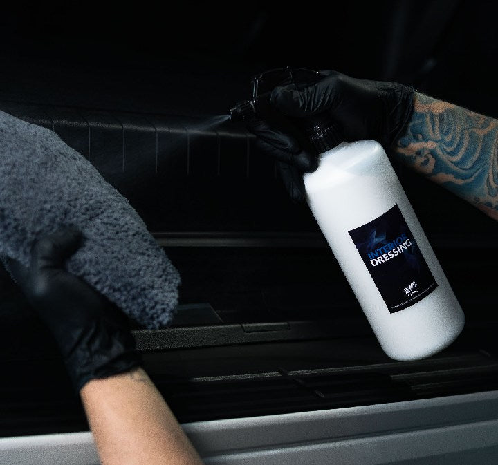 Spraying Deluxe Detail Interior Dressing onto car interior trim with a microfibre cloth ready