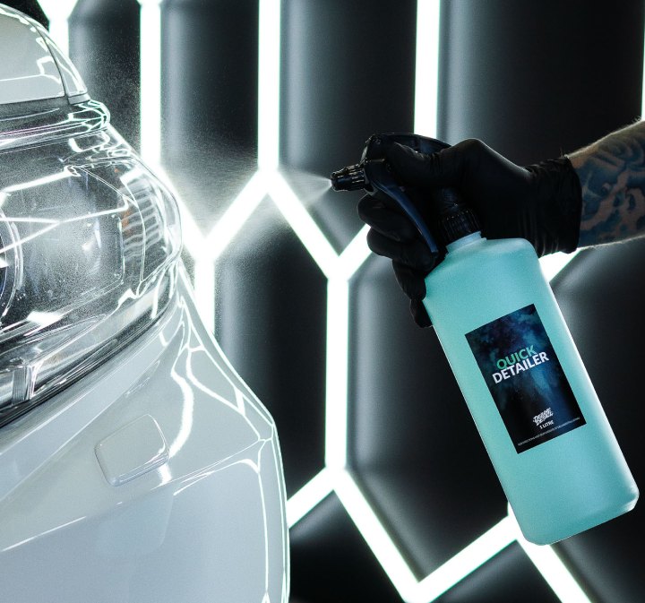 Spraying Deluxe Detail Quick Detailer over a white car in the Deluxe Detail studio